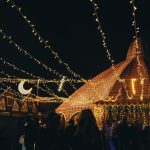 A vibrant evening market scene under string lights with people gathering in a lively atmosphere. — иллюстративное фото