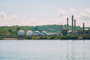 A scenic view of a coastal industrial gas storage facility with spherical tanks and tall chimneys. — иллюстративное фото